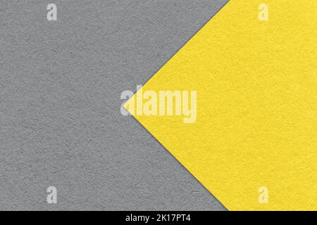 Textur von Papier grauen Hintergrund, halb zwei Farben mit gelben Pfeil, Makro. Struktur aus dichtem Bastelkarton. Fühlte mich abstrakt Hintergrund Nahaufnahme. Stockfoto