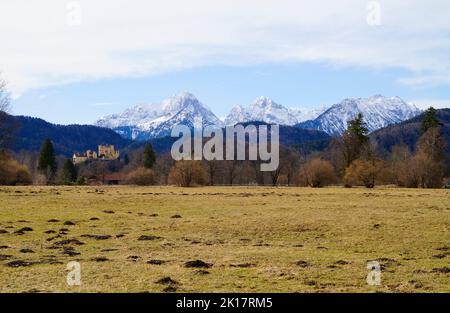 Winterliches bayerisches Alpendorf Schwangau mit den verschneiten Alpen und Schloss Hohenschwangau (Schloss Hohenschwangau) im Hintergrund (Bayern, Allgäu, Stockfoto