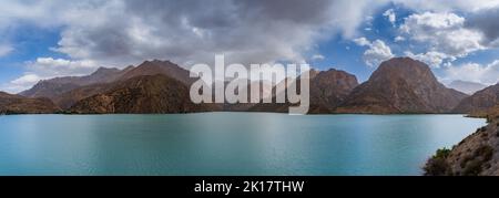 Landschaftlich reizvoller Panoramablick auf den türkisblauen Iskanderkul-See unter einem launischen Himmel, die Fann-Berge, Sughd-Region, Tadschikistan Stockfoto