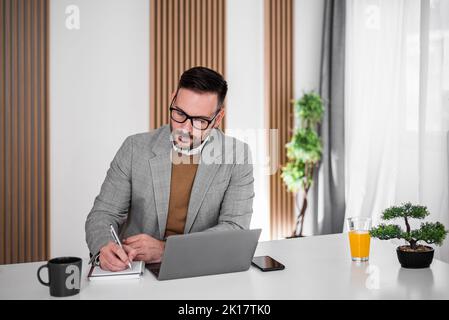 Professioneller erwachsener Firmenmitarbeiter, bärtiger männlicher Arbeiter, der während der Firmenbesprechung alles niederschrieb. Stockfoto