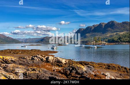 PLOCKTON WESTER ROSS SCHOTTLAND SPÄTSOMMER KÜSTENFELSEN MIT BUNTEN ALGEN UND BOOTE AUF LOCH CARRON Stockfoto