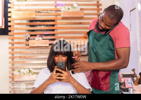 Mann und Frau in einem Friseursalon mit ihrem Telefon Stockfoto