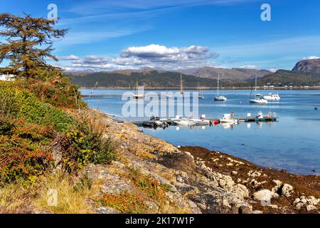 PLOCKTON WESTER ROSS SCHOTTLAND SPÄTSOMMER KÜSTE FELSEN MIT BLUMEN DIE BUCHT UND BOOTE AUF LOCH CARRON Stockfoto