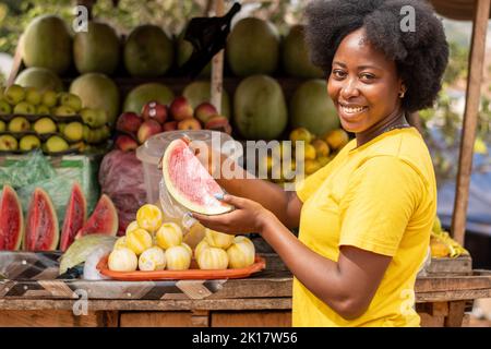 Porträt einer jungen afrikanischen Frau, die Früchte verkauft Stockfoto