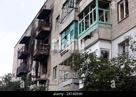 IZIUM, UKRAINE - 15. SEPTEMBER 2022 - ein alter Mann steht auf dem Balkon in einem Wohngebäude, das durch den russischen Beschuss in Izium beschädigt wurde Stockfoto