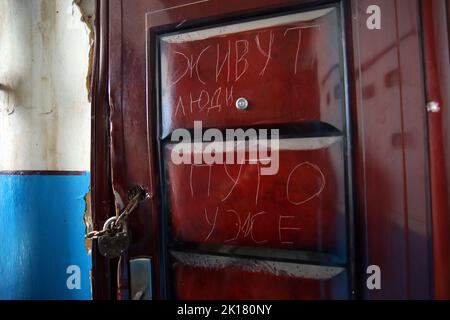 IZIUM, UKRAINE - 15. SEPTEMBER 2022 - die Inschrift "Menschen leben hier" befindet sich an der Tür zu einer von Russland befreiten Wohnung in Izium Stockfoto