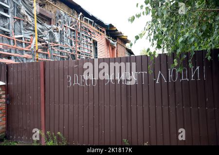 IZIUM, UKRAINE - 15. SEPTEMBER 2022 - auf dem Zaun in Izium, das von russischen Eindringlingen, Khar, befreit wurde, ist die Inschrift "Menschen leben hier" zu sehen Stockfoto