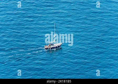 Luftaufnahme eines kleinen Segelbootes mit einer kleinen Gruppe von Menschen an Bord, im blauen Mittelmeer, Golf von La Spezia, Ligurien, Italien, Europa. Stockfoto