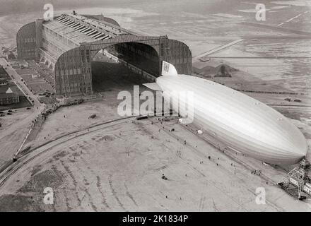 Ein in Deutschland erbauter Zeppelin Hindenburg, der am 9. Mai 1936 in den Hangar der US-Marine eindringt, dessen Nase an den beweglichen Ankerturm in Lakehurst, New Jersey, angespannt ist. Das starre Luftschiff hatte gerade einen Rekord für seine erste Nordatlantiküberquerung aufgestellt, die erste Etappe von zehn geplanten Rundfahrten zwischen Deutschland und Amerika. Stockfoto