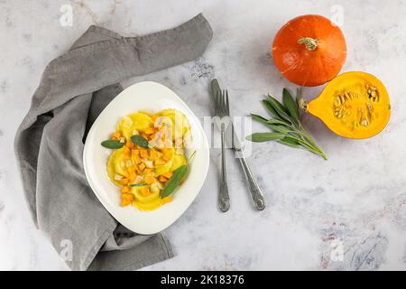 Saisonales Herbstrezept. Kürbisravioli mit Salbei, Parmesan und Olivenöl. Stockfoto