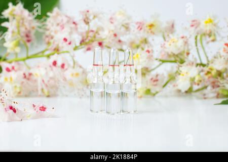 Flasche Rosskastanienextrakt, Essenz von Kastanienblüten. Blühende Zweige und Blätter von Rosskastanie. Herstellung von Medikamenten, Tabletten, Zink Stockfoto