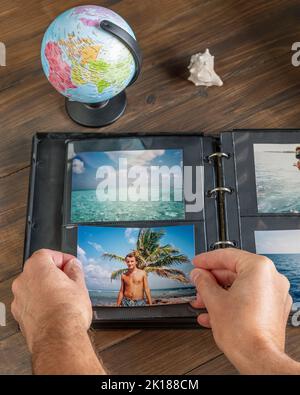 Männliche Hände fügen ein neues Foto in ein Fotoalbum mit Öffnungsringen ein Stockfoto