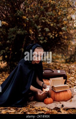 Eine junge Frau im Wald übt Halloween-Magie Stockfoto