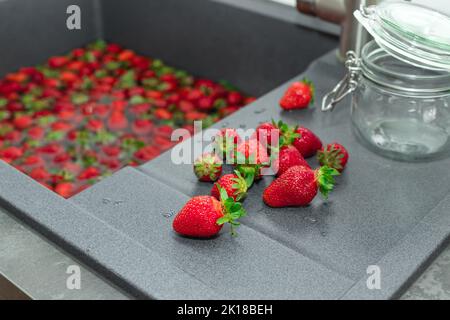 Haufen von reifen Erdbeeren auf Küche Arbeitsplatte. Prozess der Herstellung von Erdbeermarmelade oder Dessert Stockfoto