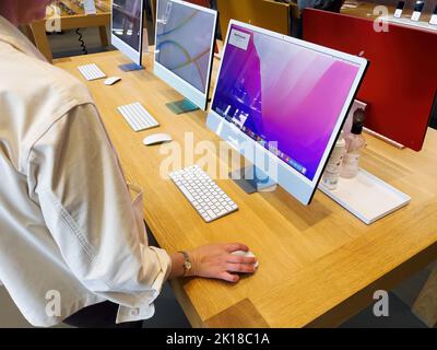 Paris, Frankreich - 9. September 2022: Seitenansicht einer Frau, die den neuesten Mac-PC mit leistungsfähigem M1-Chip betrachtet und versucht, herauszufinden, wie macOS funktioniert Stockfoto