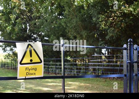 Ein Schild auf einem Zaun in Campbell Park, Milton Keynes: 'Flying Discs'. Dies bezieht sich auf Disc Golf, das im Park gespielt wird. Stockfoto