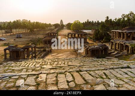 Hampi, Karnataka, Indien: Allgemeiner Blick bei Sonnenuntergang auf die Ruinen des alten Hampi Bazaar Marktplatzes. 7. Jahrhundert Sree Virupaksha Tempel im Hintergrund. Stockfoto
