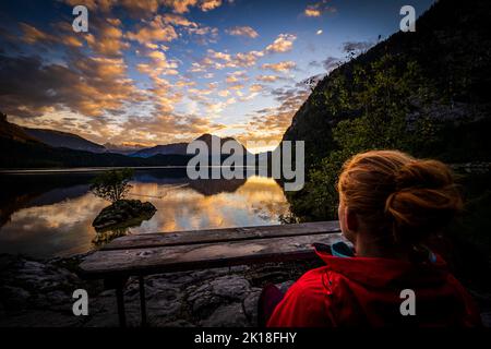 Die Wandererin genießt einen atemberaubenden Blick auf den alpinen Altausseer See in Ausseer Land, Steiermark, Österreich, und einen atemberaubenden Sonnenuntergang Stockfoto