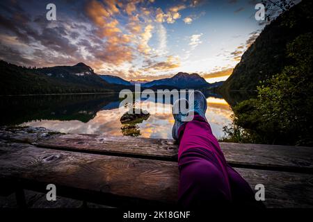 Wanderweibchen mit Beinen auf Picknicktisch vor einem atemberaubenden Blick auf den Altausseer See in der Ausseer Land Region, Steiermark, Österreich Stockfoto