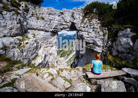Wanderweibchen genießen den Blick durch das sogenannte Loser-Fenster, einen Felsbogen auf dem Loser Berg, Ausseer Land, Steiermark, Österreich Stockfoto