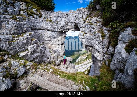 Wanderweibchen genießen den Blick durch das sogenannte Loser-Fenster, einen Felsbogen auf dem Loser Berg, Ausseer Land, Steiermark, Österreich Stockfoto