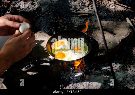 Frühstück im Wald. Frühstück auf einer Wanderung. Klassisches Ei in einer Pfanne am Lagerfeuer Stockfoto