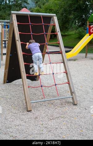 Ein Junge (nicht erkennbar) klettert auf einem Kinderspielplatz eine Seilleiter Stockfoto