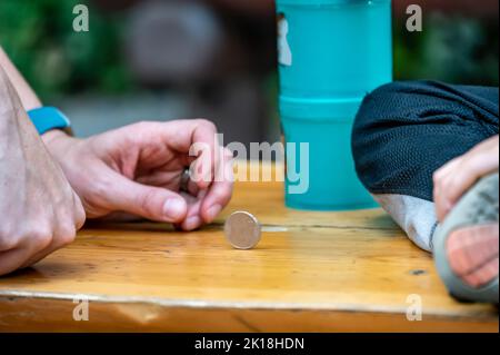 Zwei Spieler spielen ein Spiel mit einer sich drehenden Münze, um Zeit zu verstreichen. Stockfoto