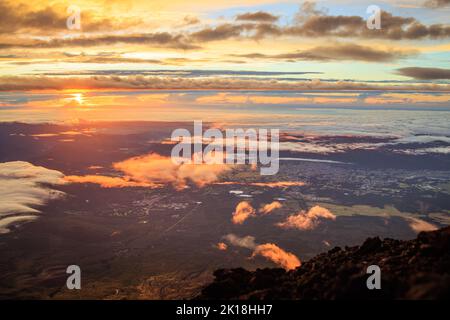 Am frühen Morgen trifft die Sonne auf Wolkentüffeln nahe dem Gipfel des Mt. Fuji Stockfoto