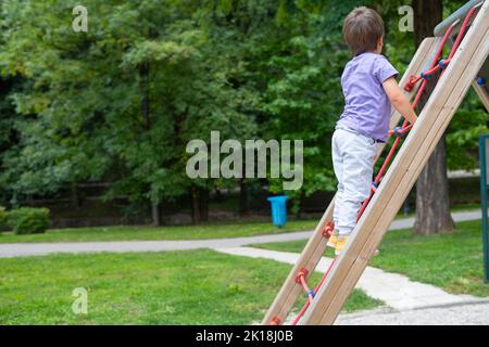 Ein Junge (nicht erkennbar) klettert auf einem Kinderspielplatz eine Seilleiter Stockfoto