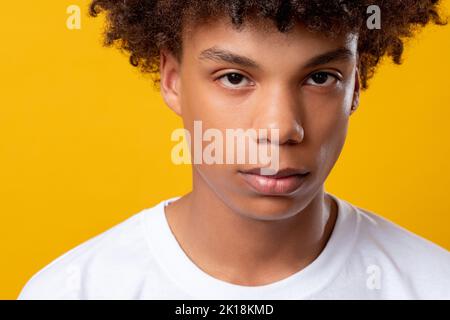 Schwarze Leben sind wichtig. Gefühle von Teenagern. Junger afrikanischer Kerl, der die Kamera isoliert auf orangefarbener Nahaufnahme ansieht. Soziale Toleranz. Melodische Emotion. Werbung Stockfoto