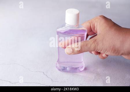 Halten Sie einen Behälter für Mundwasser mit der Hand Stockfoto