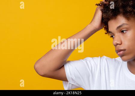 Gefühle von Teenagern. Schwarze Leben sind wichtig. Frustrierter junger afrikanischer Mann, der Kopf auf orangefarbenem Kopierraum isoliert hält. Ethnische Toleranz. Melodische Stimmung. A Stockfoto