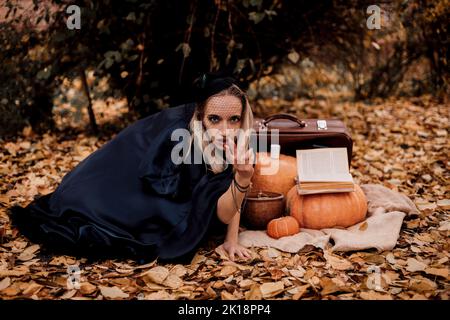 Eine junge Frau im Wald übt Halloween-Magie Stockfoto