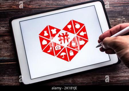 Vancouver, KANADA - Sep 16 2022 : Logo der chinesischen E-Commerce-Plattform Pinduoduo auf Tablet auf Holztisch. Mann Hand hält Stylus Stift Stockfoto