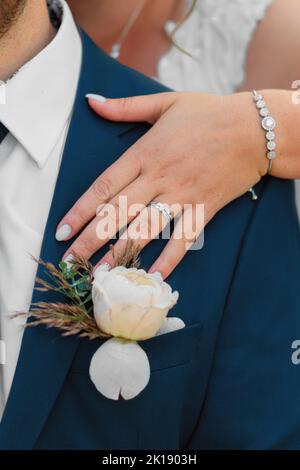 Die Braut legt seine Hand auf die Brust des Bräutigams und zeigt ihren Ring Stockfoto