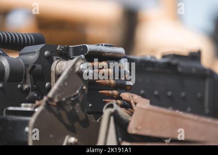 Nahaufnahme eines Maschinengewehrs, das mit Kugeln vor verschwommenem Hintergrund beladen ist Stockfoto