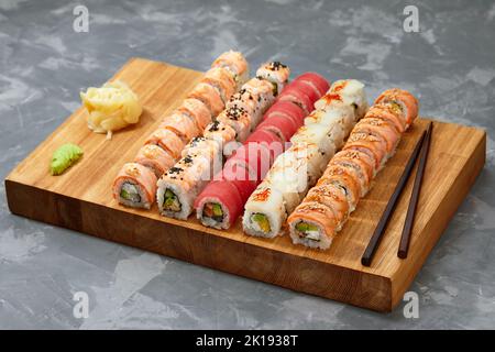 Draufsicht Hintergrund mit Satz von bunten verschiedenen Arten von Sushi-Rollen auf Holzbrett platziert Stockfoto