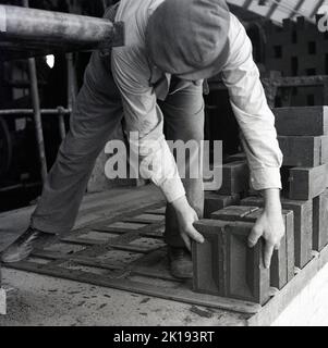 1950er Jahre, historisch, ein männlicher Arbeiter, mit einer flachen Kappe, stapelte neu gefeuerte Ziegel bei der London Brick Company, Bedford, England, Großbritannien. Stockfoto
