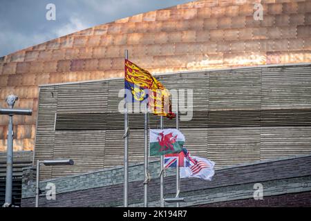 Cardiff, Großbritannien. 16. September 2022. Die Union Jack und die walisische Flagge fliegen am halben Mast neben der Royal Standard Flagge als Zeichen des Respekts für Ihre Majestät die Königin während des Besuches von König Charles III und Camilla, Queen Consort im Senedd Gebäude in Cardiff, Großbritannien, heute Nachmittag. Der Besuch des britischen Königspaares in Wales ist der letzte Halt auf ihrer Tour durch die vier Hauptstädte, anlässlich der Thronbesteigung des Königs nach dem Tod seiner Mutter, Königin Elizabeth. Quelle: Phil Rees/Alamy Live News Stockfoto