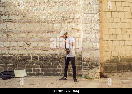 Montenegro Kotor 27. Mai 2022, der Junge spielt ein Musikinstrument auf der Straße, Editorial Porträt eines verärgerten Mädchens, das an einem Kaffeetisch sitzt Stockfoto