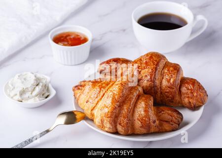 Frische süße Croissants mit Quark und Aprikosenmarmelade zum Frühstück. Stockfoto