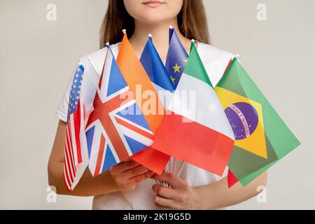 Weltgemeinschaft. Globale Organisation. Frau mit internationalen Flaggen isoliert auf unscharfer Lichthintergrund. Politische Konvention. Vereinte Nationen. Gover Stockfoto