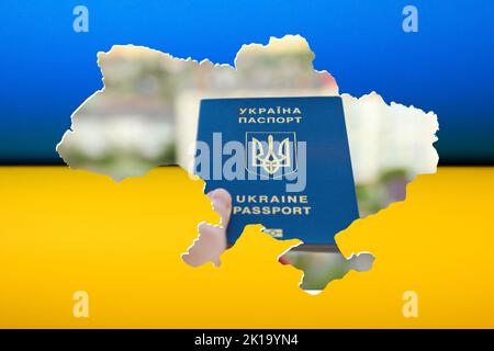 Unschärfe-Pass eines Bürgers der Ukraine in einer weiblichen Hand auf Flagge Ukraine Hintergrund, Nahaufnahme. Inschrift auf Ukrainisch. Ukraine-Pass. Kriegsperson Stockfoto