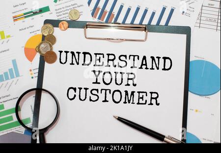 Leeres Blatt, Stift und zerknitterte Papierkugeln auf grauem Tisch, flach liegend. VERSTEHEN SIE IHREN KUNDEN Stockfoto