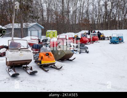 NISSWO, MN - 21 JAN 2022: Mehrere Marken alter Vintage-Motorschlitten sitzen auf einem schneebedeckten Parkplatz im Winter. 1950s, 1960s, 1970s und 1980s Jahrgangswein Stockfoto