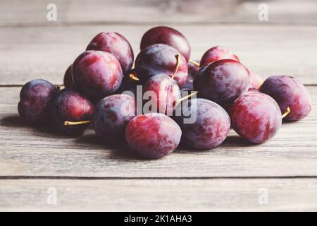 Pflaumen im Stapel auf Holztisch, geerntete Pflaumenfrüchte im Herbst, Platz kopieren Stockfoto