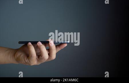 Das Telefon befindet sich auf dem Handdeckel der Person. Konzept der Kommunikationstechnik. Stockfoto