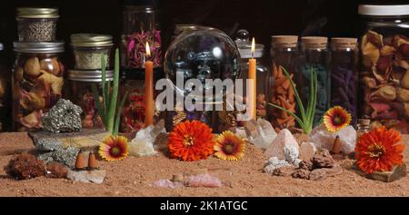 Kristallkugel mit Kerzen und Chakra-Steinen auf dem australischen roten Sand Meditationsaltar Stockfoto