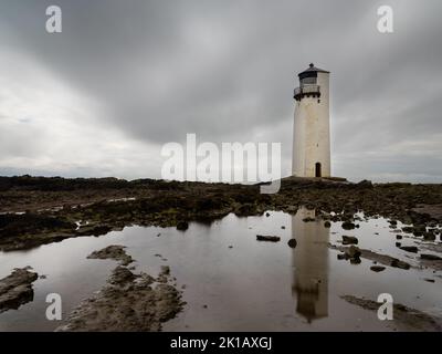 Ein Blick auf den historischen Southerness Lighthouse in Schottland mit Reflexionen in Gezeitenbecken im Vordergrund Stockfoto